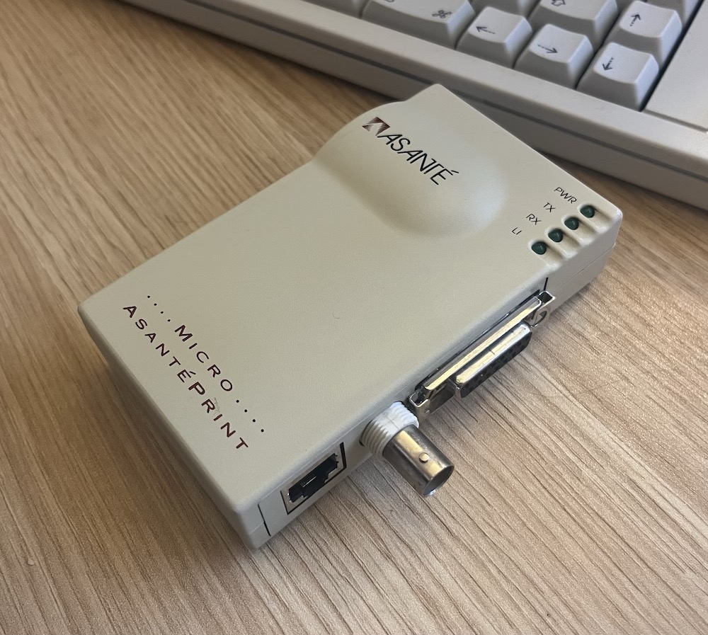 Boitier Asanté qui comporte du côté visible un port Ethernet, un BNC, un DB15 et derrière un port série mini-DIN